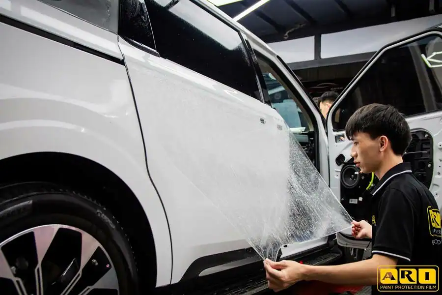 kỹ thuật viên đang dán phim ppf ari cho cửa xe kia carnival